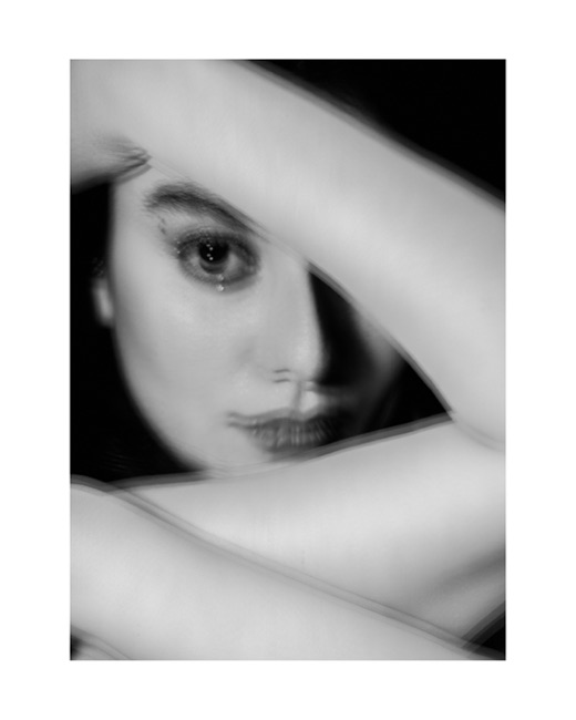 Keshabyan, photographed by Lilit L Hovhanni — a close black and white portrait, one eye framed between raised arms.