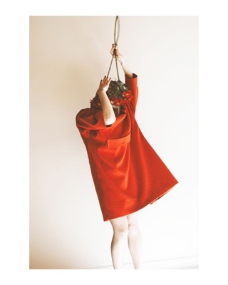 Syuzi, photographed by Lilit L Hovhanni — a figure in a red coat against a white wall, head hidden, a rope above.