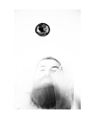 Vengardium leviosa, photographed by Lilit L Hovhanni — a man’s face in bright white light, a dark disc floating above.